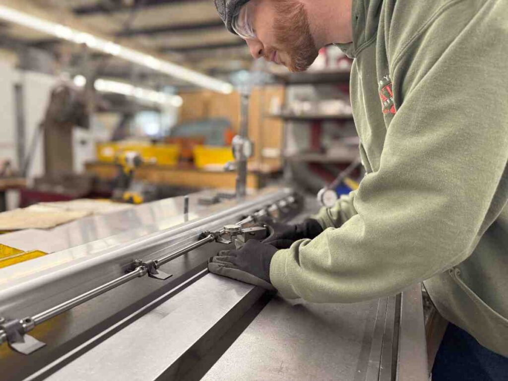 Factory worker measuring aftermarket gripper bar at Conway Machine